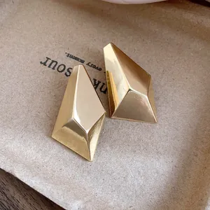 Macro shot of gold-plated geometric faceted stud earrings with high-shine finish.