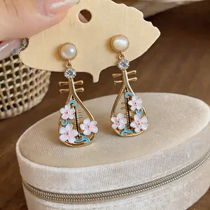 Primo piano di eleganti orecchini pipa in stile cinese con fiori di smalto rosa e perle