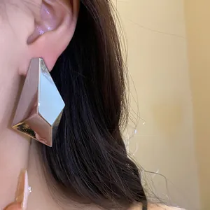 Detailed macro view of a silver geometric faceted stud earring worn on a model ear