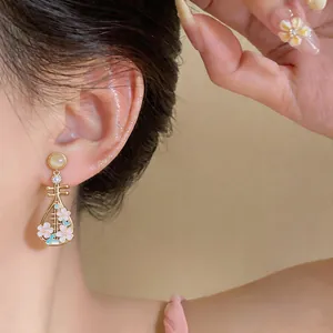 Primo piano di orecchini a forma di liuto in stile cinese con fiori rosa e dettagli in zircone