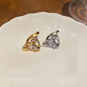 Primo piano di orecchini a clip a cuore in oro e argento con zirconi e stelle