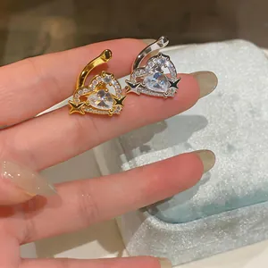 Primo piano di eleganti clip per orecchie a cuore in oro e argento con stelle di zirconi