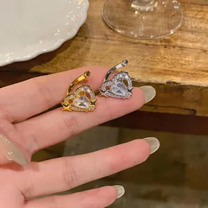 Dettaglio macro di polsini per orecchie a cuore con zirconi e stelle in oro e argento
