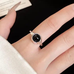 Detailed close-up of a minimalist silver open ring featuring an oval black stone