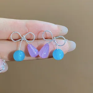 Primo piano di dolci orecchini a lobo a fiocco di moda in resina con perline blu e viola