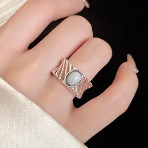 Detail of silver hollow wavy ring band featuring a vintage oval white stone inlay