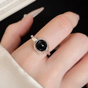 Detailed macro close-up view of an oval black stone ring with silver hammered metal texture.