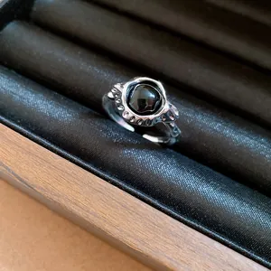 Close-up of a minimalist vintage oval black stone hollow open ring in a jewelry box.