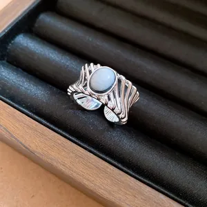 Detailed close-up of a vintage silver open ring with an oval white stone and hollow frame