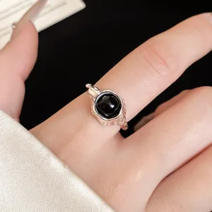Close-up of a vintage oval black stone ring with silver molten texture on finger