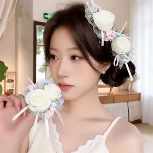 Close-up view of an elegant white chiffon rose hair clip and matching floral wrist accessory