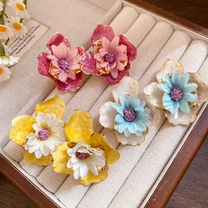 Primer plano de pendientes de flores en 3D en rojo, azul y amarillo vivo