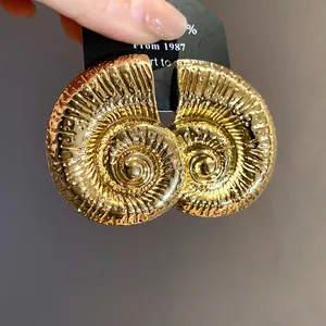 Vista detallada de pendientes náutilo dorados vintage con textura grabada única