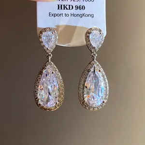 Dettaglio ad alta risoluzione di orecchini pendenti con zircone a goccia e montatura halo.