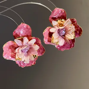 Primer plano detallado de pendientes de flores de esmalte rosa con pétalos de tela suave