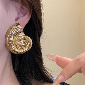 Primer plano detallado de un pendiente de metal dorado con forma de caracola retro