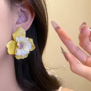 Vista detallada de elegantes pendientes florales amarillos y blancos en la oreja de modelo