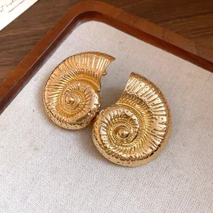 Vista detallada de pendientes vintage de concha de nautilo dorados con textura fina.
