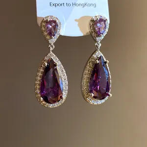 Primo piano di eleganti orecchini a goccia con zirconi viola e bordo pavé