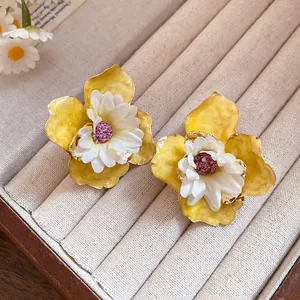 Primer plano de elegantes pendientes de flores amarillas y blancas en bandeja