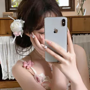 Detail view of a white chiffon rose hair clip worn by a model in a mirror selfie