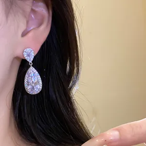 Primo piano di eleganti orecchini a goccia in argento con zirconi scintillanti su modella.