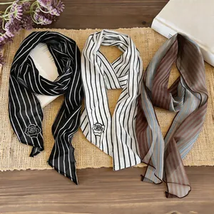 Macro view of three narrow striped neck scarves with rose detail on a straw mat