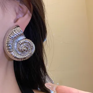 Primer plano de pendiente de concha de nautilo plateado vintage con espiral