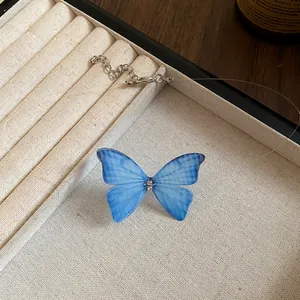 Close-up detail of a blue translucent butterfly pendant on a transparent choker necklace