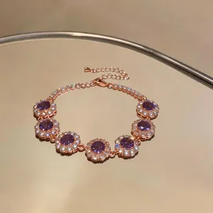 Elegante bracciale in oro rosa con grappoli di zirconi viola su superficie riflettente.