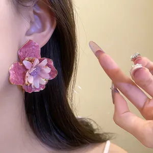 Detalle de elegantes pendientes de flor rosa usados para un look de verano chic