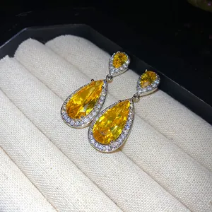 Primo piano di orecchini a goccia in zircone giallo con pavé di pietre trasparenti.