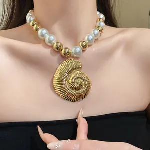 Primer plano de collar vintage con perlas y cuentas doradas y colgante de concha