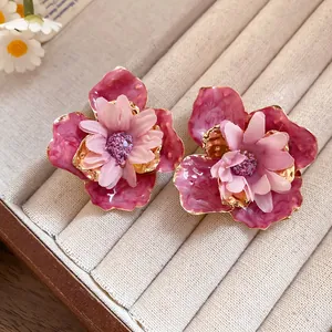 Primer plano de pendientes de flor rosa con delicados pétalos de tela y brillo