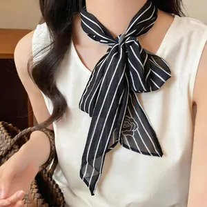 Detailed view of black and white striped neckerchief with rose motif on a model