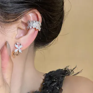 Detailed macro view of sparkling silver flower earrings and ear cuff on model's ear
