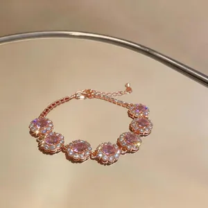 Primo piano di un bracciale in oro rosa con fiori di zircone rosa su uno specchio