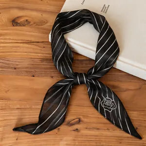 Detail macro view of a stylish black striped neck scarf with a white rose print