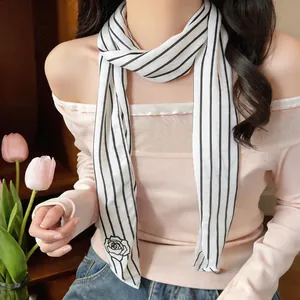 Close-up detail of a elegant black and white striped neck scarf with rose print