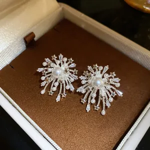Detail view of firework-inspired pearl earrings with sparkling zircon stars in a gift box