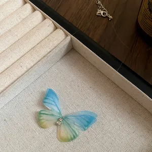 Detail view of a butterfly choker necklace with blue and green gradient wings.