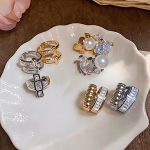 Elegant French-style ear cuffs with pearls and crystals on a white shell plate