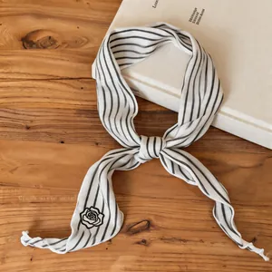 Close-up detail of a chic black and white striped neck scarf with an elegant rose emblem