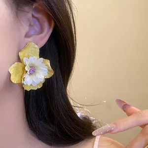 Detalle de un elegante pendiente de flor blanco y amarillo usado por una modelo en primer plano.
