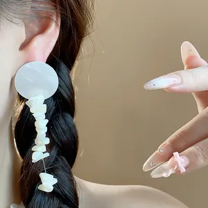 Primer plano de elegantes pendientes colgantes de concha blanca usados por una modelo