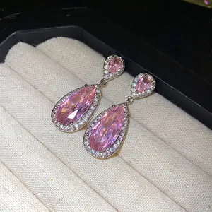 Primo piano di eleganti orecchini a goccia in zircone rosa con alone di pietre e cofanetto.