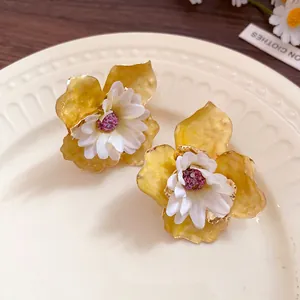 Primer plano de pendientes de flores de verano con pétalos amarillos y centro blanco