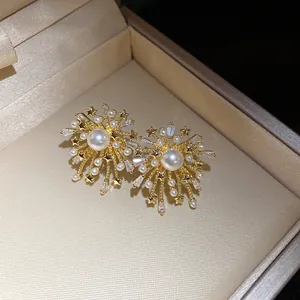 Detailed macro view of gold firework stud earrings with pearls and zircon in a box