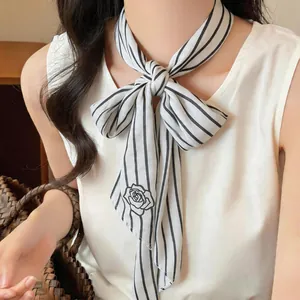 Close-up detail of a minimalist black and white striped skinny scarf with rose print