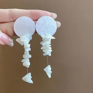 Vista de detalle de pendientes en acetato blanco con adornos de conchas puras